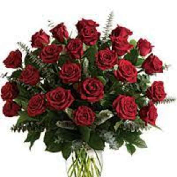 Tall arrangement of long-stemmed red roses in a clear glass vase