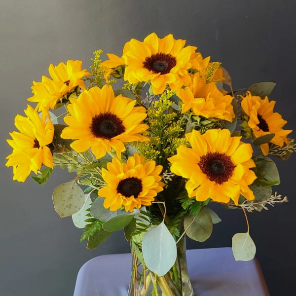 Yellow sunflowers arranged in a clear glass vase