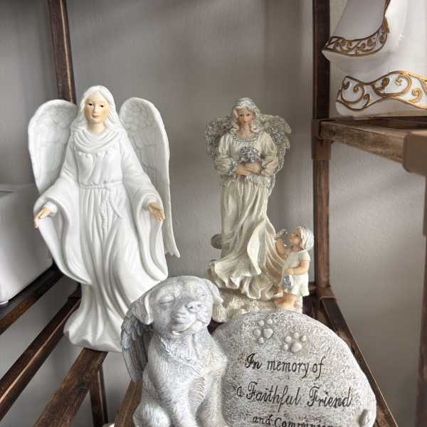 Memorial figurines with angels, a winged dog, and an engraved stone for a faithful friend and companion.