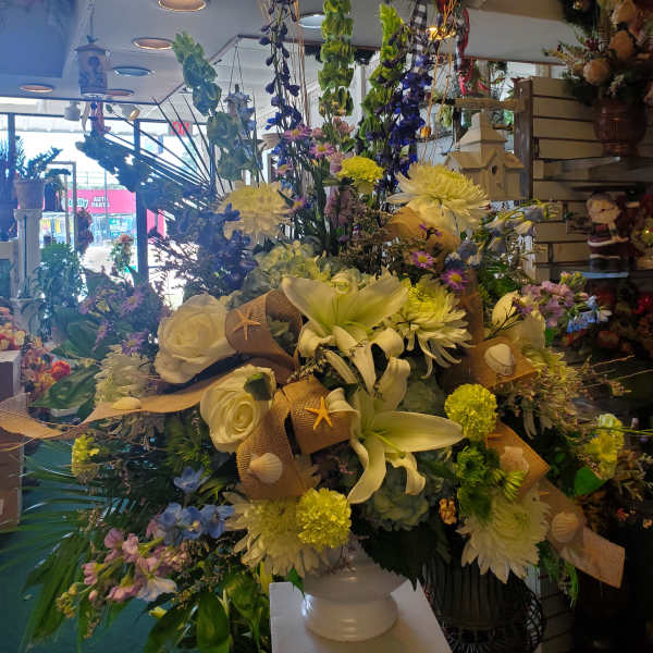 Large mixed floral arrangement in a white vase with lilies and roses
