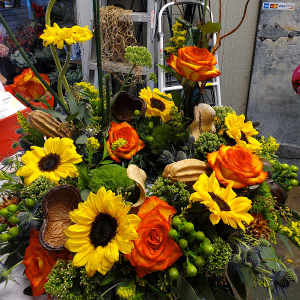 Orange roses and yellow sunflowers arranged in a dense floral display