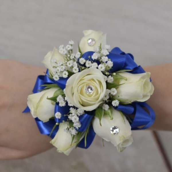 White rose wrist corsage with blue ribbon and rhinestone accents