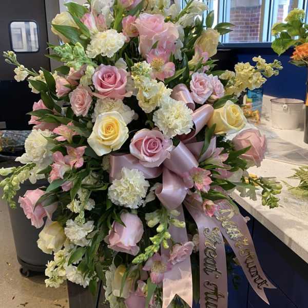 Large pink and white floral arrangement with ribbon streamers