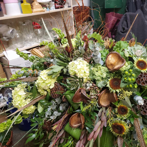 Large tropical floral arrangement with sunflowers, hydrangeas, and green accents