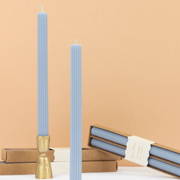 Two light blue ribbed taper candles with boxes and a gold holder