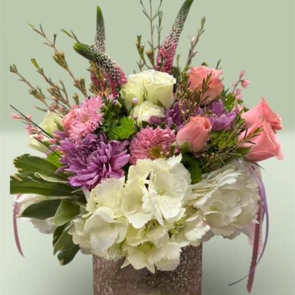 Mixed bouquet of pink, purple, and white flowers in a textured vase