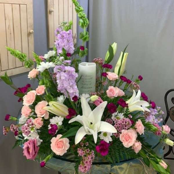 Large floral sympathy arrangement with white lilies, pink roses, and lavender blooms