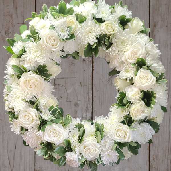 White floral wreath with roses and chrysanthemums on a wooden background