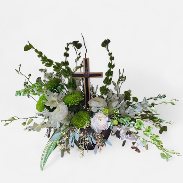 White and green floral arrangement with a wooden cross centerpiece