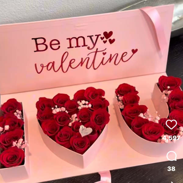 Heart-shaped boxes of red roses with a pink Valentine card