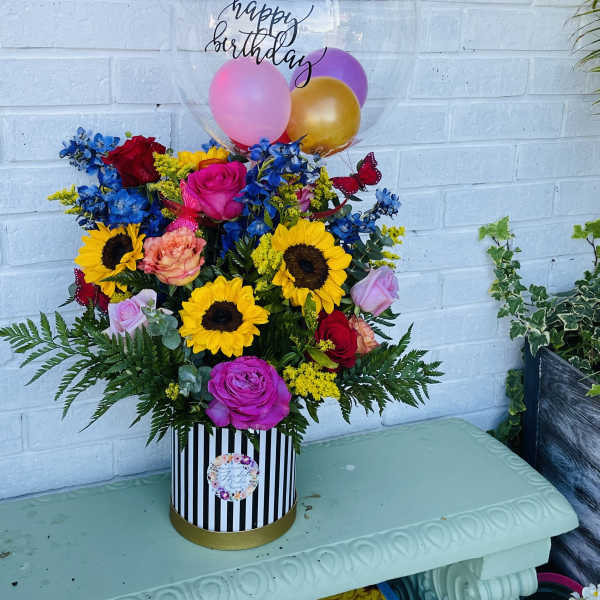 Birthday flower arrangement with balloons in a striped box