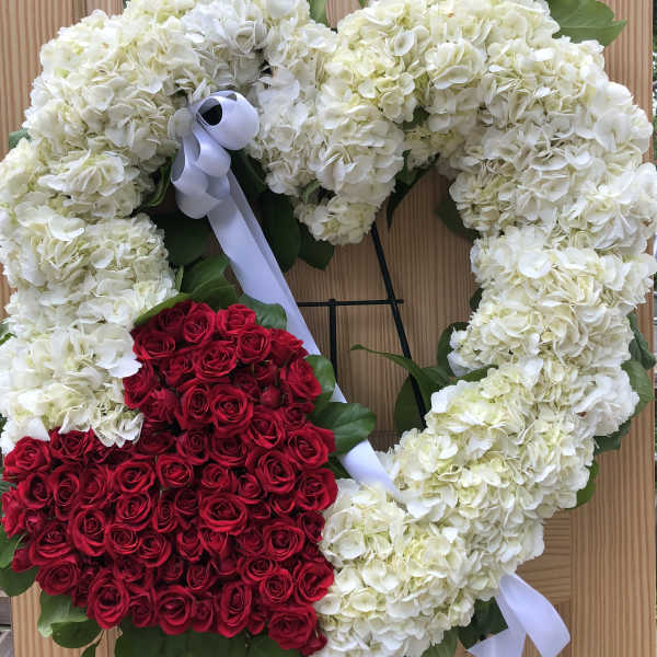 Heart-shaped floral wreath with white hydrangeas and red roses on a stand