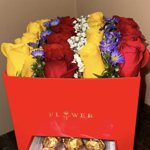 Red and yellow roses in a red gift box with chocolates in a drawer below