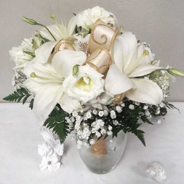 White floral bouquet in a clear glass vase with gold ribbon accents