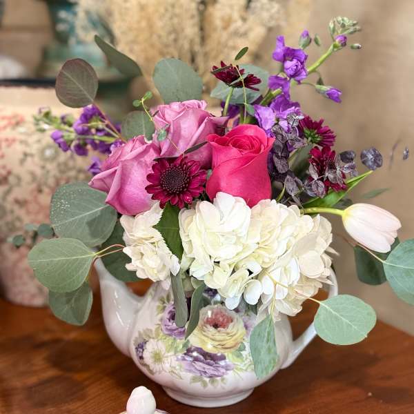 Bouquet of pink and white flowers in a floral teapot vase