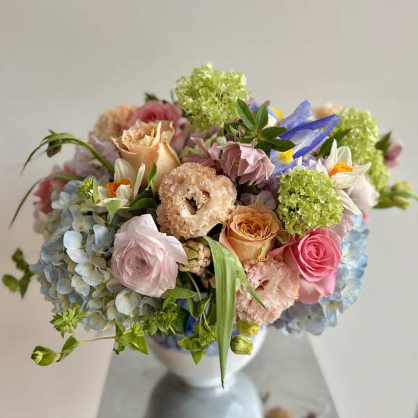Pastel bouquet of roses, hydrangeas, and mixed blooms in a white vase