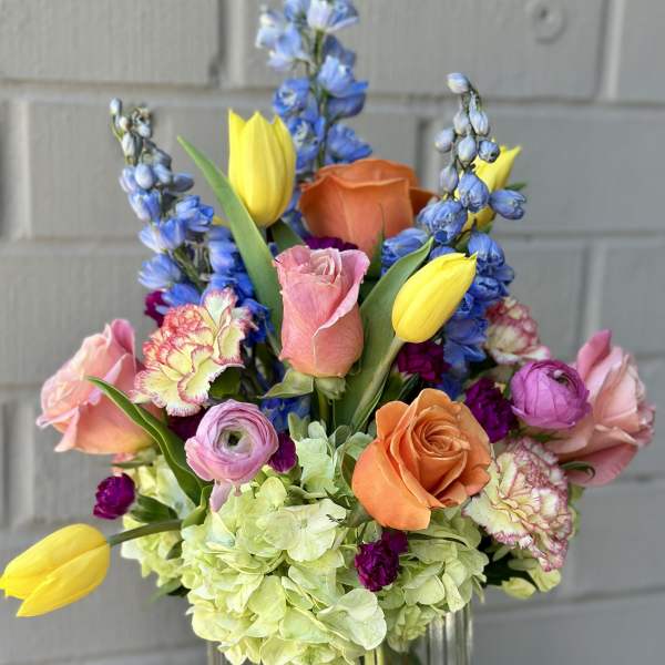 Colorful mixed bouquet in a clear glass vase with roses and tulips