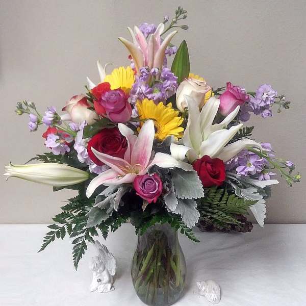 Mixed bouquet of roses, lilies, and daisies in a glass vase