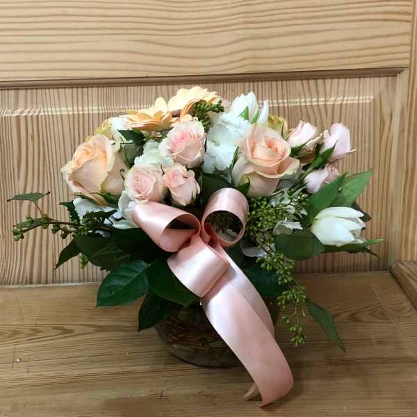 Bouquet of pale pink and white flowers with a pink ribbon in a basket