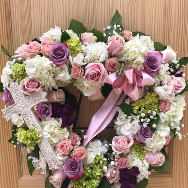 Heart-shaped floral wreath with pink and white roses and a ribbon bow