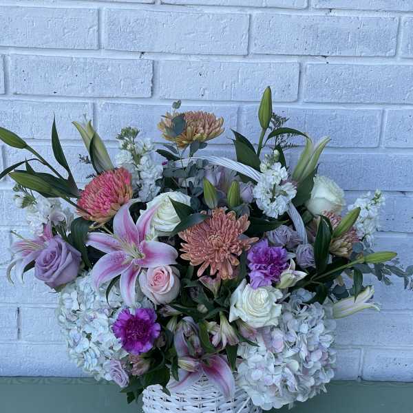 Basket arrangement of pink, lavender, and white flowers