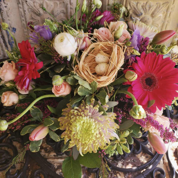 Mixed bouquet with pink gerberas, roses, and a small nest with eggs