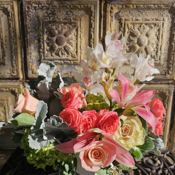Bouquet of pink and cream roses with white orchids in a white vase