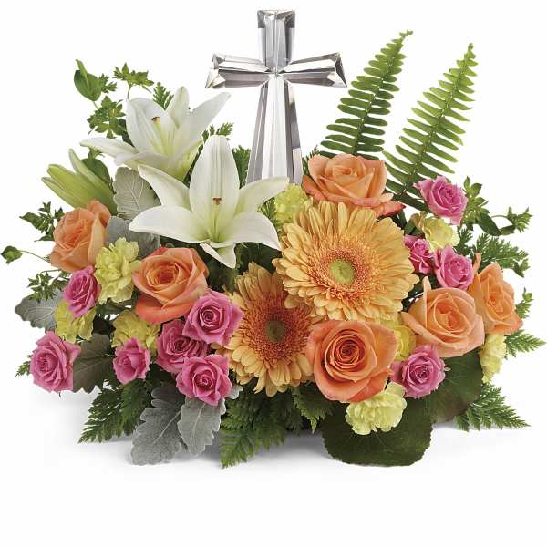 Floral arrangement with white lilies, roses, gerbera daisies, and a silver cross
