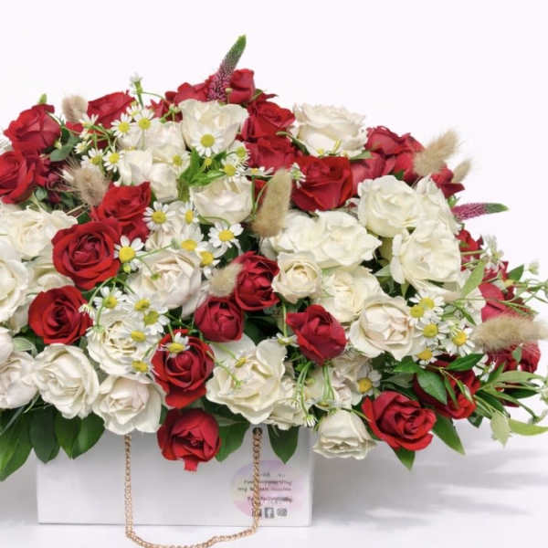 Red and white rose arrangement in a white box with small daisy accents