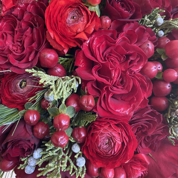Close-up bouquet of red roses and ranunculus with berry accents