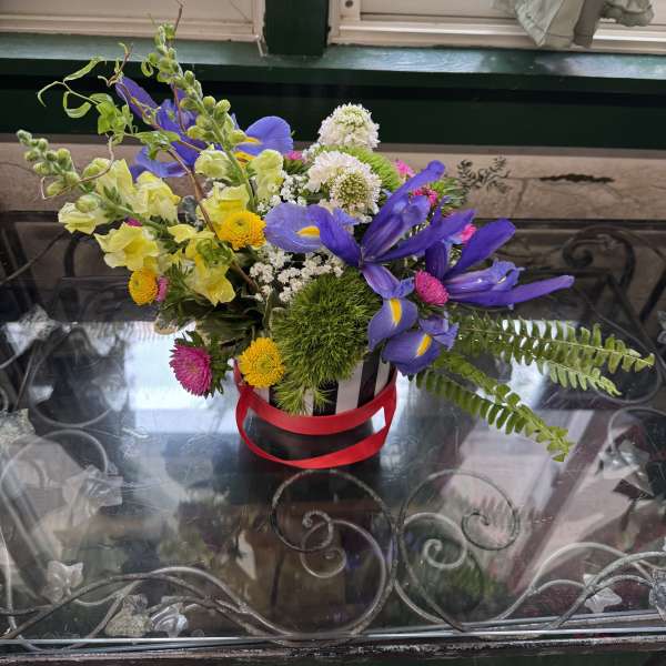 Mixed bouquet with purple irises and yellow snapdragons in a striped container