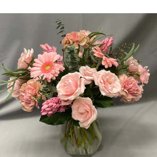 Pink flower arrangement with roses and gerbera daisies in a clear glass vase