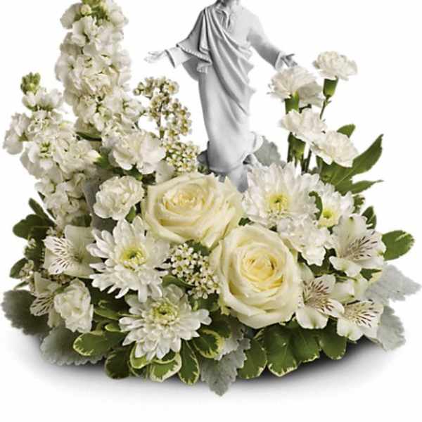 White floral arrangement with a small statue of Jesus at the center