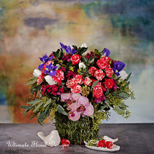 Mixed bouquet in a woven basket with roses, orchids, and purple blooms