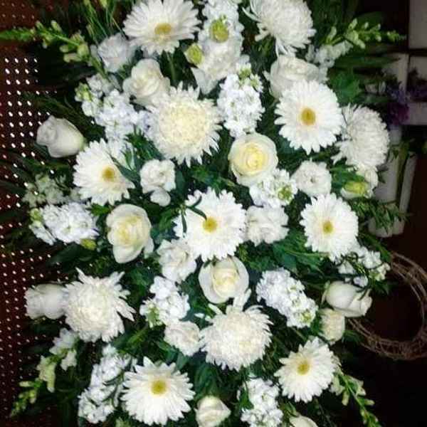 White funeral spray with daisies, roses, and chrysanthemums