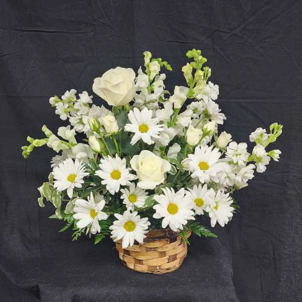 White roses and daisies arranged in a woven basket