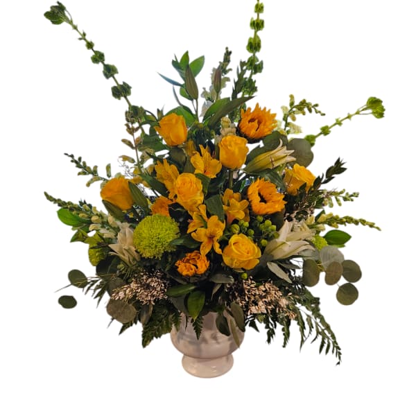 Yellow floral arrangement in a white vase with tall greenery accents