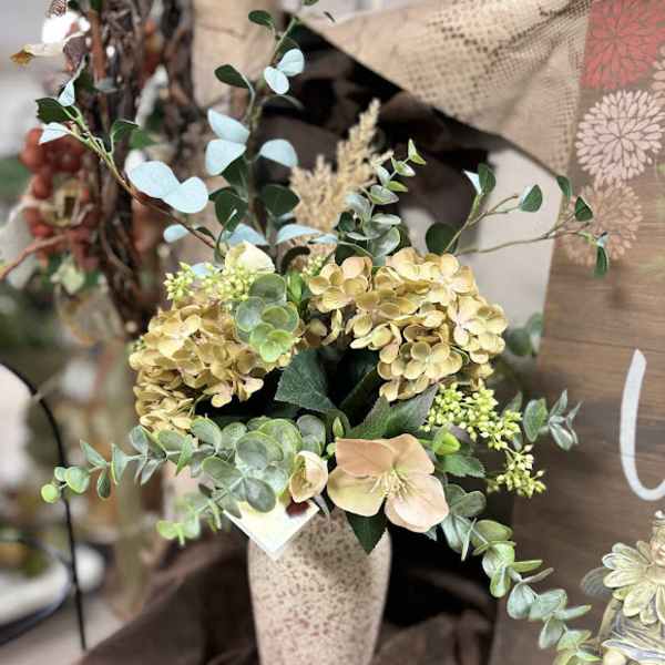 Arrangement of pale hydrangeas and greenery in a tall vase