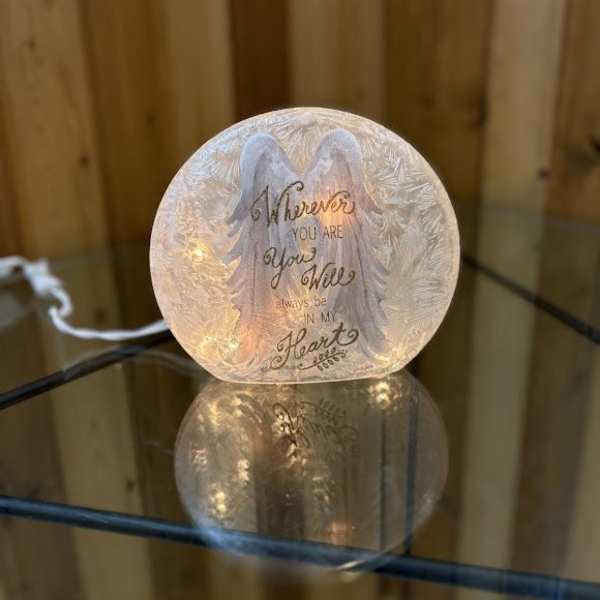 Glowing memorial light with angel wings and a sympathy message