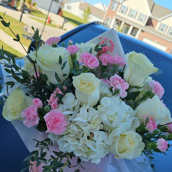 Bouquet of white roses, pink carnations, and white hydrangea in pink wrapping