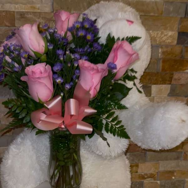 Pink roses and purple daisies in a glass vase with a pink ribbon