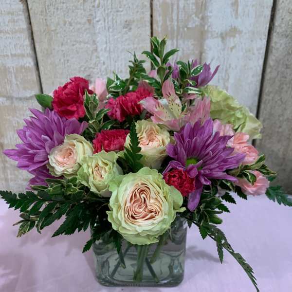 Bouquet of pink and purple flowers in a square glass vase