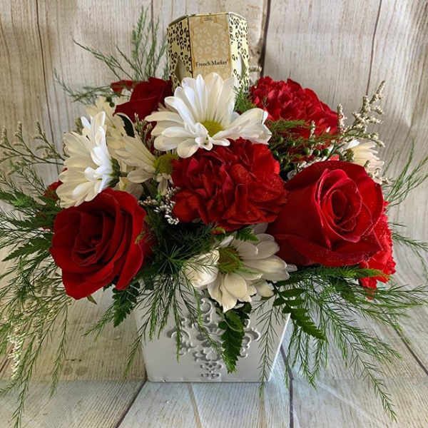 Red roses and white daisies in a decorative white container