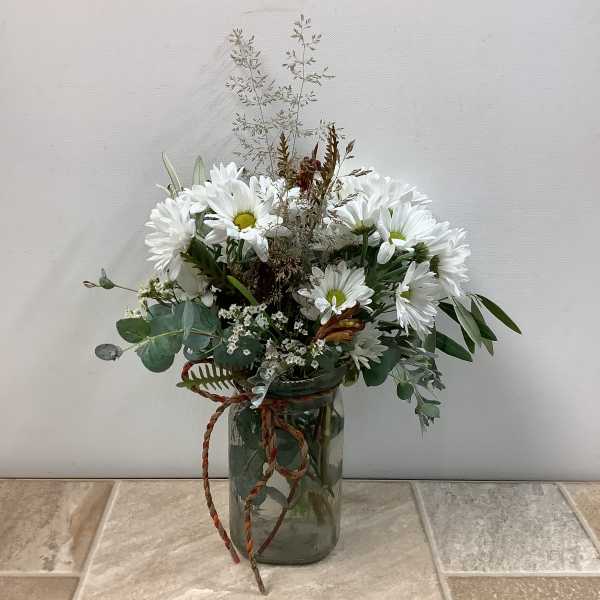 White daisy bouquet in a glass jar with greenery