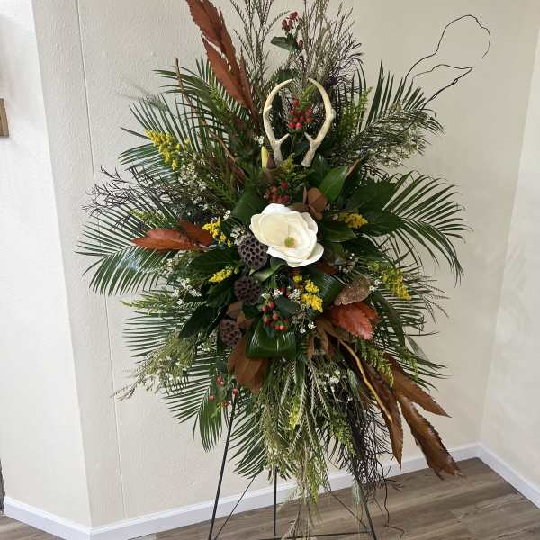 Tall floral standing spray with white bloom and mixed greenery on an easel