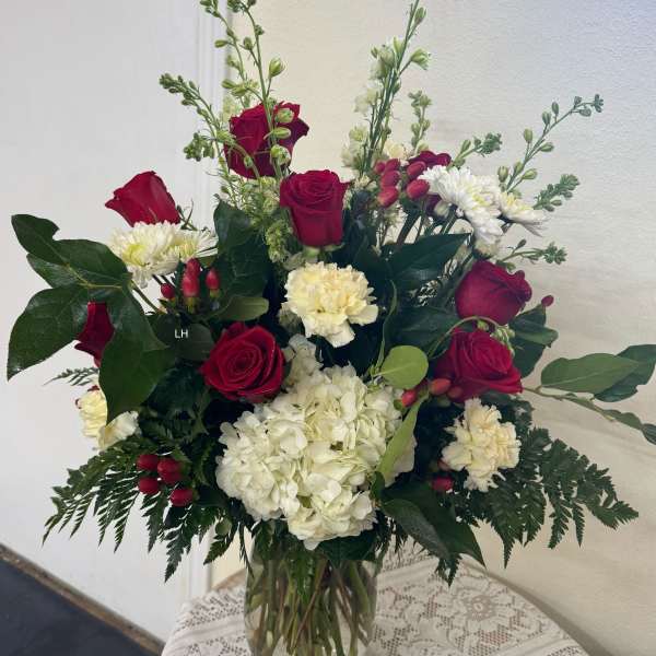 Red roses and white flowers in a clear glass vase
