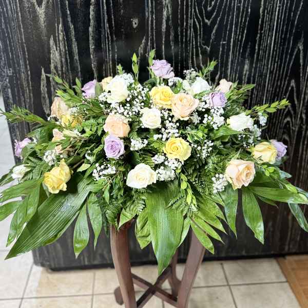 Pastel roses and baby's breath in a low arrangement on a stand