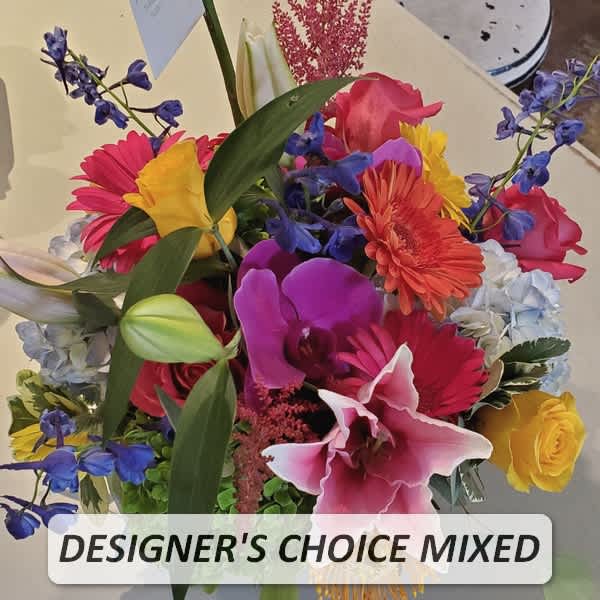 Bright mixed arrangement with lilies, roses, orchids, gerbera daisies, hydrangea, and delphinium in a vase