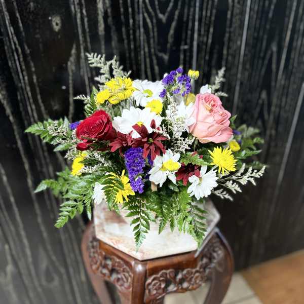 Mixed bouquet with roses and daisies in a square vase