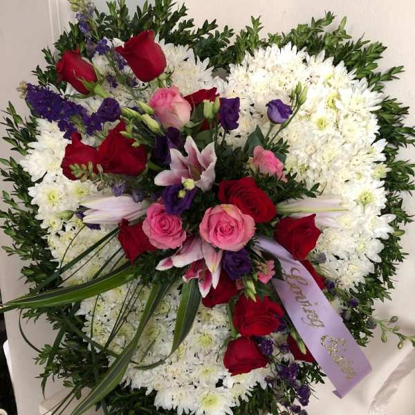 Large floral spray with red and pink roses, white chrysanthemums, and purple accents